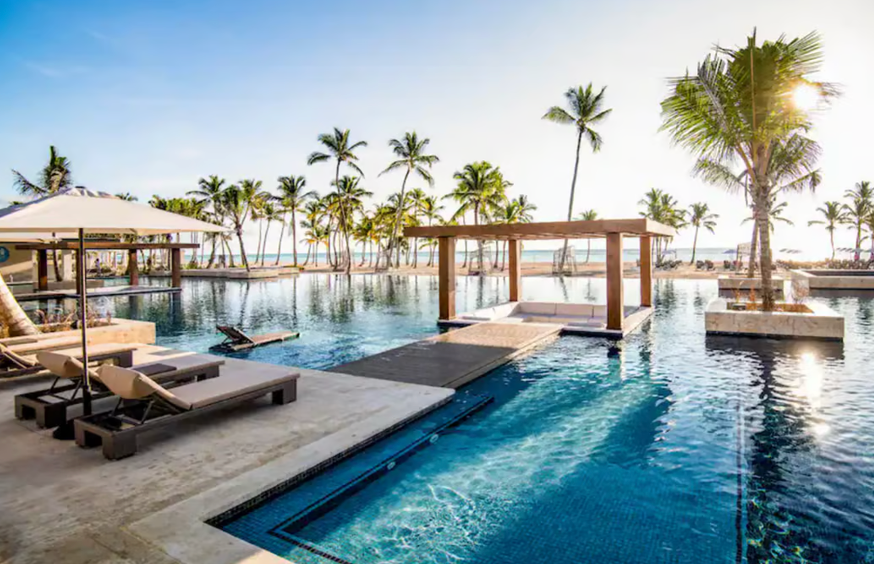 A view of a Hyatt all-inclusive resort with a pool, lounge chairs, and palm trees.