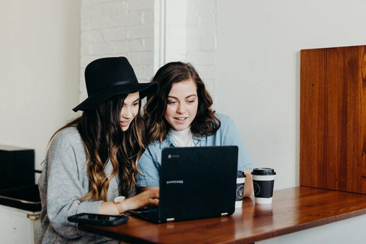 Two girls are looking at a laptop and shopping with an online shopping portal.